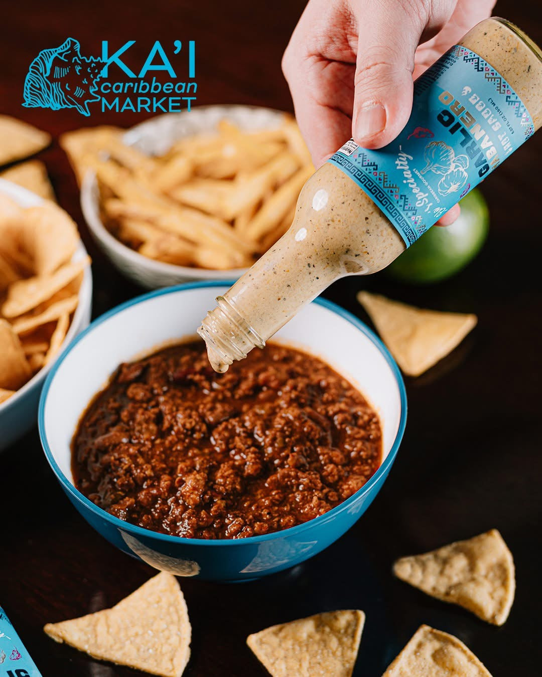 Person dipping a Garlic Habanero hot sauce by Kai Caribbean Market into a bowl of chili.