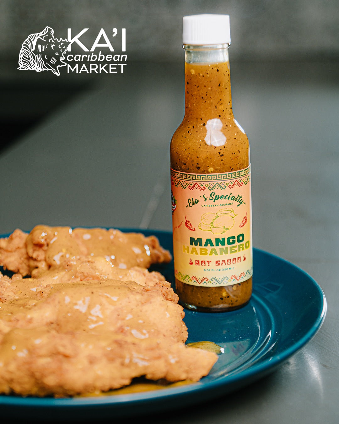Kai Caribbean Market Mango Habanero hot sauce bottle served with breaded chicken cutlets on a plate